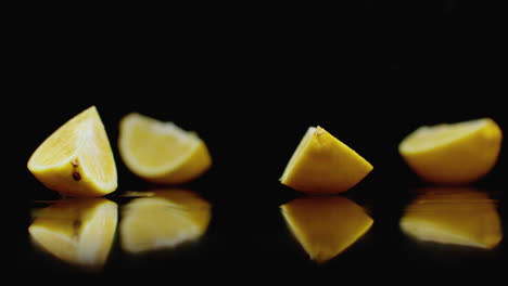 juicy sliced ​​yellow lemon fall into 4 parts glass with water splashes in slow motion on a dark background