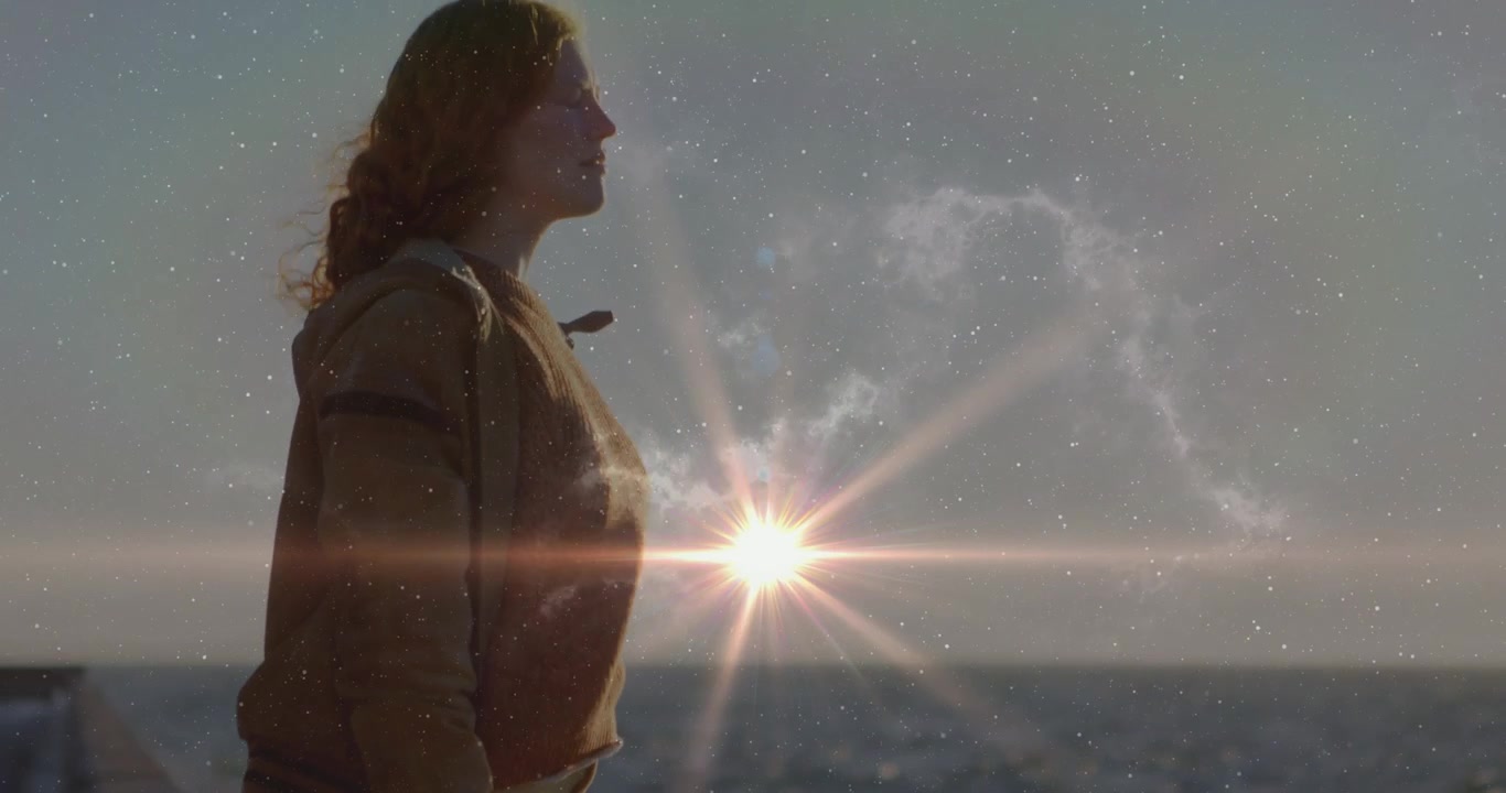 Mulher em pé no píer olhando para cima, reflexo solar se alinhando perto do peito revelando sobreposição de nebulosa para demonstração de tecnologia