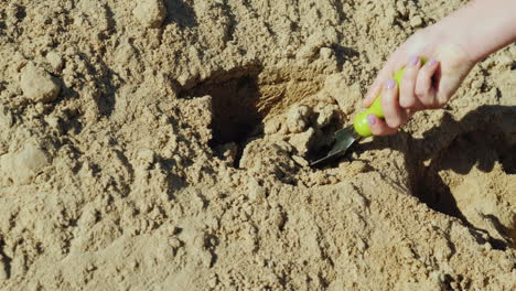 A-Hand-With-A-Small-Garden-Shovel-Gathers-Sand-From-A-Large-Pile