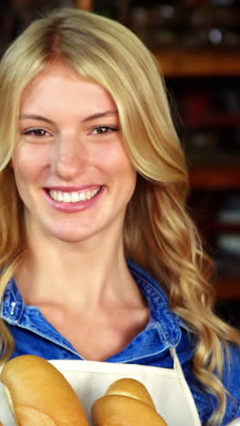 smiling woman holding a basket of baguettes in organic shop