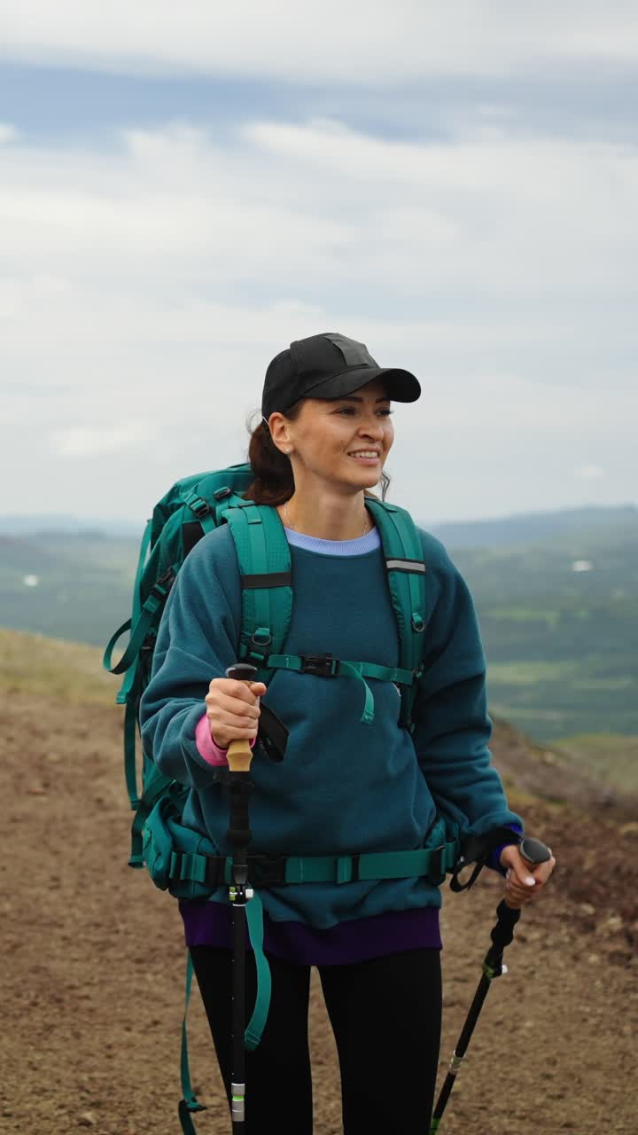 Donna che fa escursioni in salita su un sentiero di montagna con zaino e bastoncini