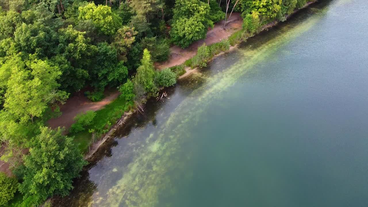 Aerial above scenic nature landscape with clear lake water and green trees in near Breda, Netherlands.
