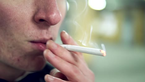 Close-Up-view-of-young-blonde-man-in-a-black-suit-with-a-bow-tie-smoking-a-cigarette-in-the-parking.-Slow-Motion