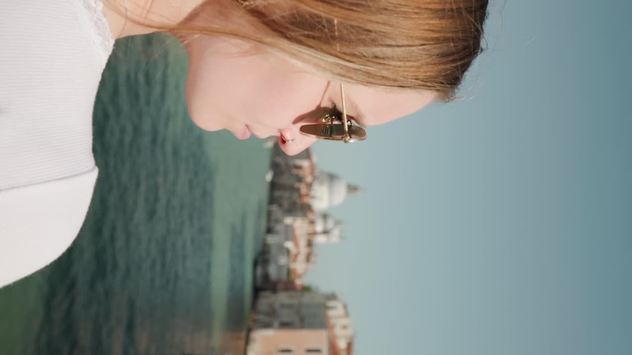 Vertical Shot Of Blonde Girl Tourist With Braided Hair And Sunglasses Watching At Famous Sites Along Grand Canal In Venice, Italy