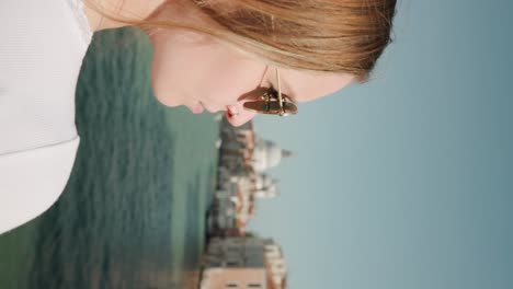 Vertical-Shot-Of-Blonde-Girl-Tourist-With-Braided-Hair-And-Sunglasses-Watching-At-Famous-Sites-Along-Grand-Canal-In-Venice,-Italy