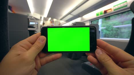 manos sosteniendo un teléfono con una pantalla verde en el tren