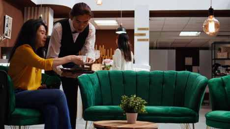 waiter serving cup of coffee for customer in lounge area