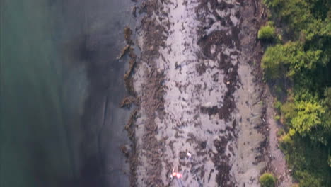 toma aérea volando sobre una playa de arena con gente caminando debajo disfrutando de las olas del océano atlántico lamiendo la costa de maine