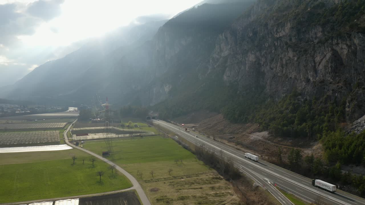 Drone footage of highway running through fields and cliffs in Tyrol.