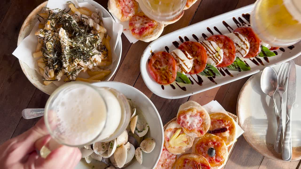 A vibrant beachside meal with beer, pizza, clams, and bruschetta under natural lighting in Phuket, Thailand