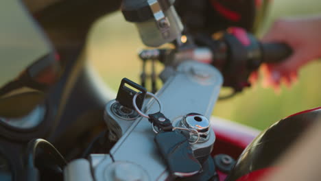 a close-up of a person's hand inserting a key into the ignition of a motorcycle