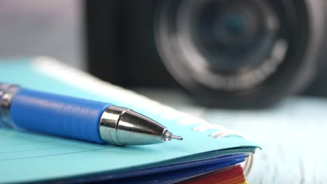 Pen on Notebook with Camera in Background