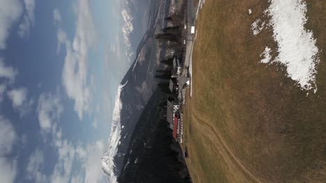 Video-Vertical:-Drone-Aéreo-Volando-Sobre-Casas-En-Una-Montaña-Con-Campos-Y-árboles-Además