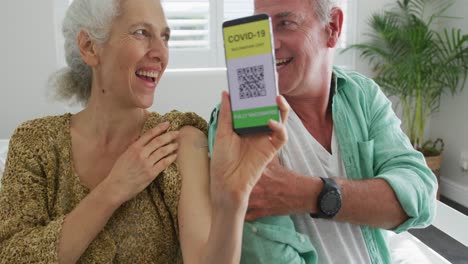 Happy-caucasian-senior-couple-showing-plaster-after-vaccination-and-covid-passport