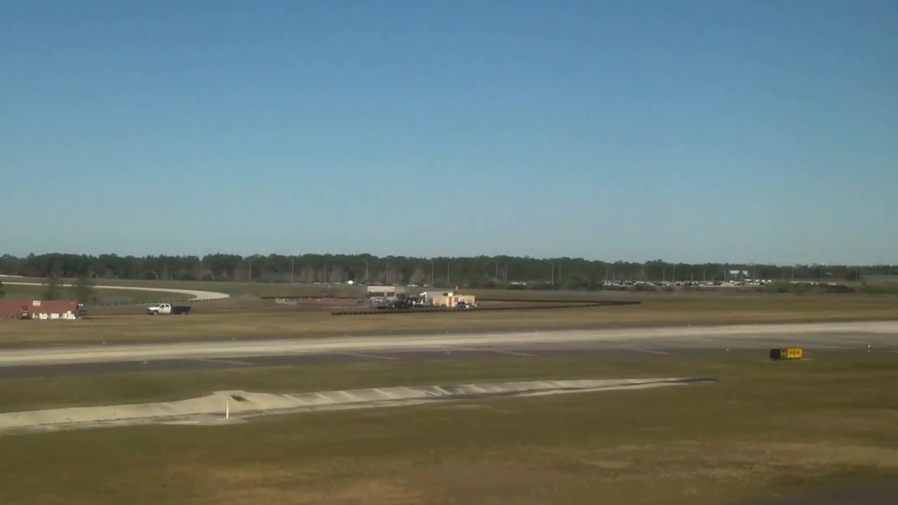Filmato ripreso dal finestrino di un jet commerciale in atterraggio all'aeroporto internazionale di Orlando (MCO). Mostra l'ombra dell'aereo a terra, la segnaletica della pista e la torre di controllo del traffico aereo