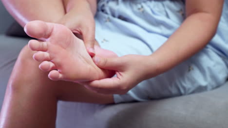 close-up of woman pressing and squezzing her own foot while giving herself a foot massage