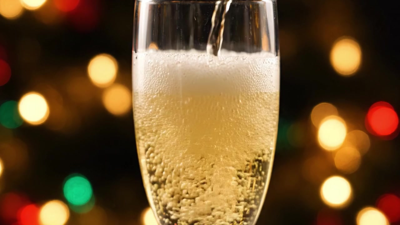 Questa immagine celebrativa mostra una bevanda frizzante versata in un elegante bicchiere, impreziosita da splendide luci bokeh che esaltano un'atmosfera di festa.