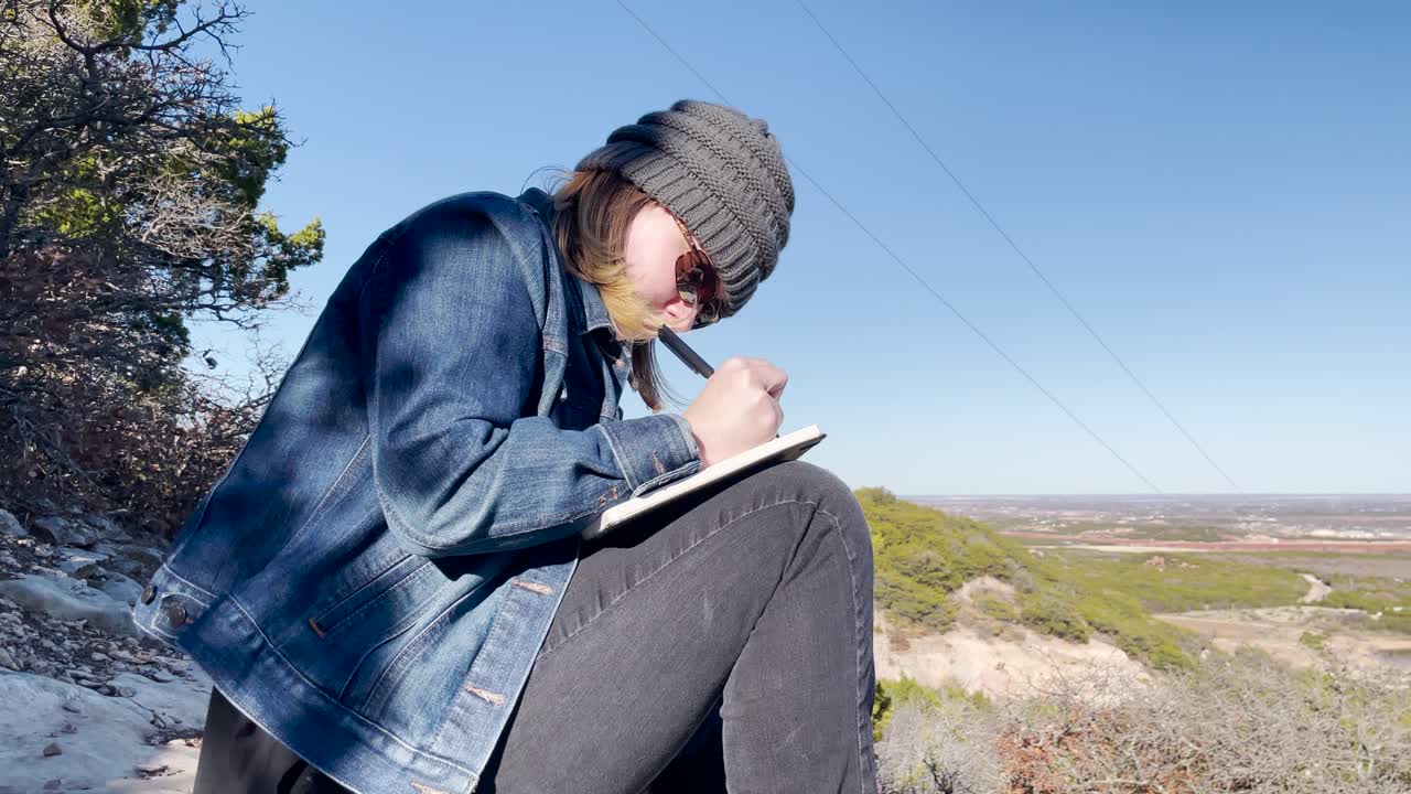 wide shot of person writing in a journal outside in nature