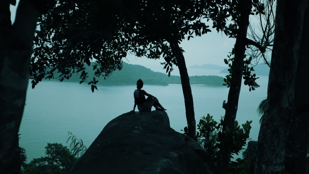 Woman sitting on a rock overlooking the ocean