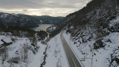 Narrow-Road-Overlooking-Beautiful-Scenery-In-The-Snowy-Mountains-Of-Norway-In-Winter---aerial-shot