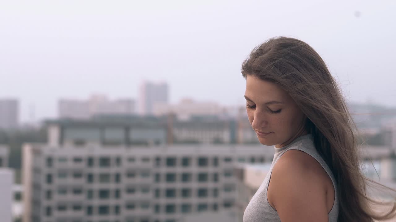 el viento sopla sobre la hermosa mujer sentada contra los hoteles borrosos
