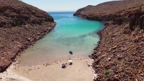 aerial: small boat and beachgoers moored on deserted empty beach, espiritu santo island, mexico