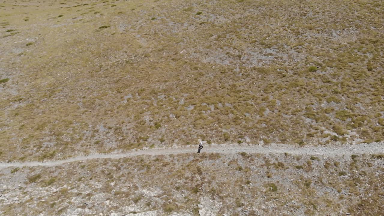 toma aérea de un hombre caminando, caminando solo en la montaña griega kissavos en la región de tesalia, vista de drones, ruta en la montaña, estilo de vida deportivo, manera saludable de dejar el paisaje marrón caminando