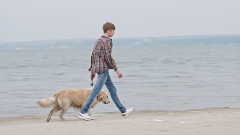 teenage boy walking dog on beach