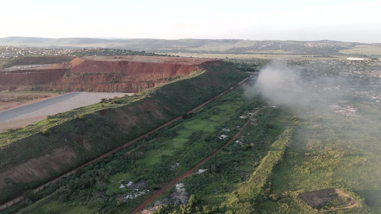 Slow rotating drone shot captures the coexistence of a rural township village and a waste processing plant in South Africa