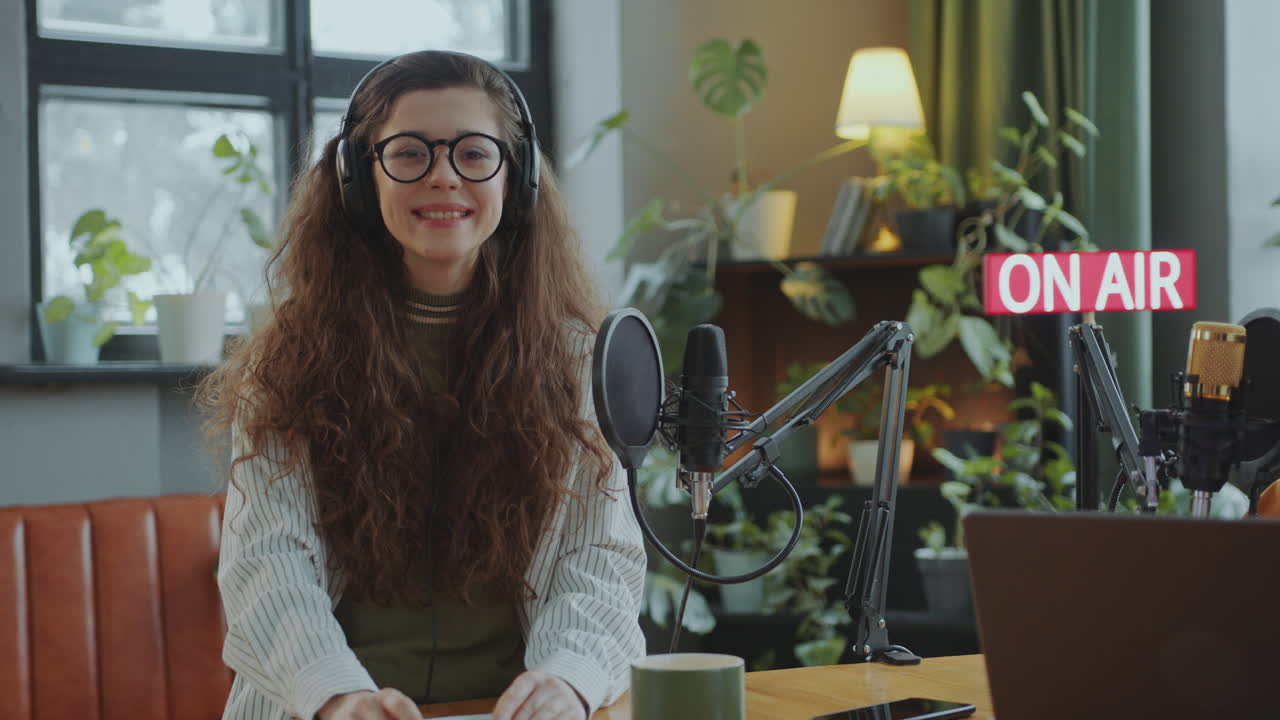 Portræt af glad ung pige i podcastoptagestudie.