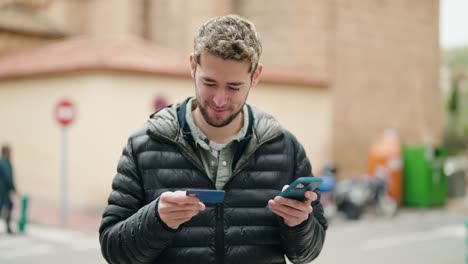 young man using smartphone and credit card at street