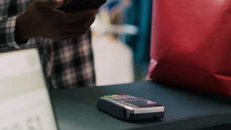cliente poniendo el teléfono en el terminal pos