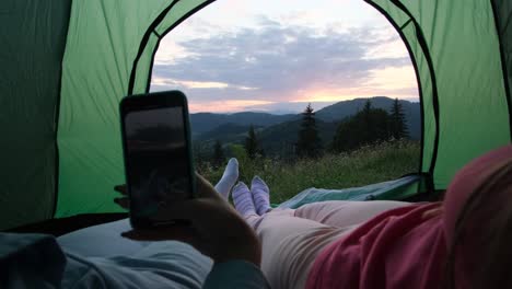 tourists with tents rest in the mountains on a meadow a view of a tourist campsite with tents and an electric car where tourists are resting on a glade among trees and fog creeping over the forest a tent city on a hike on an early sunny foggy morning