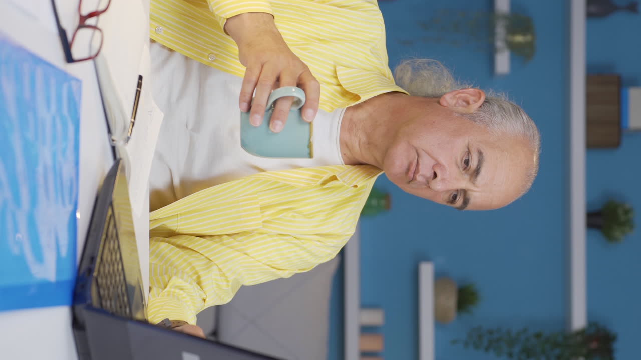 Vertical video of Home office worker old man has tooth sensitivity.