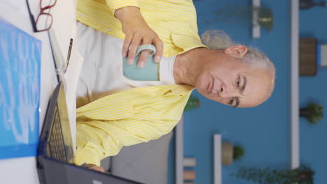 vertical video of home office worker old man has tooth sensitivity.