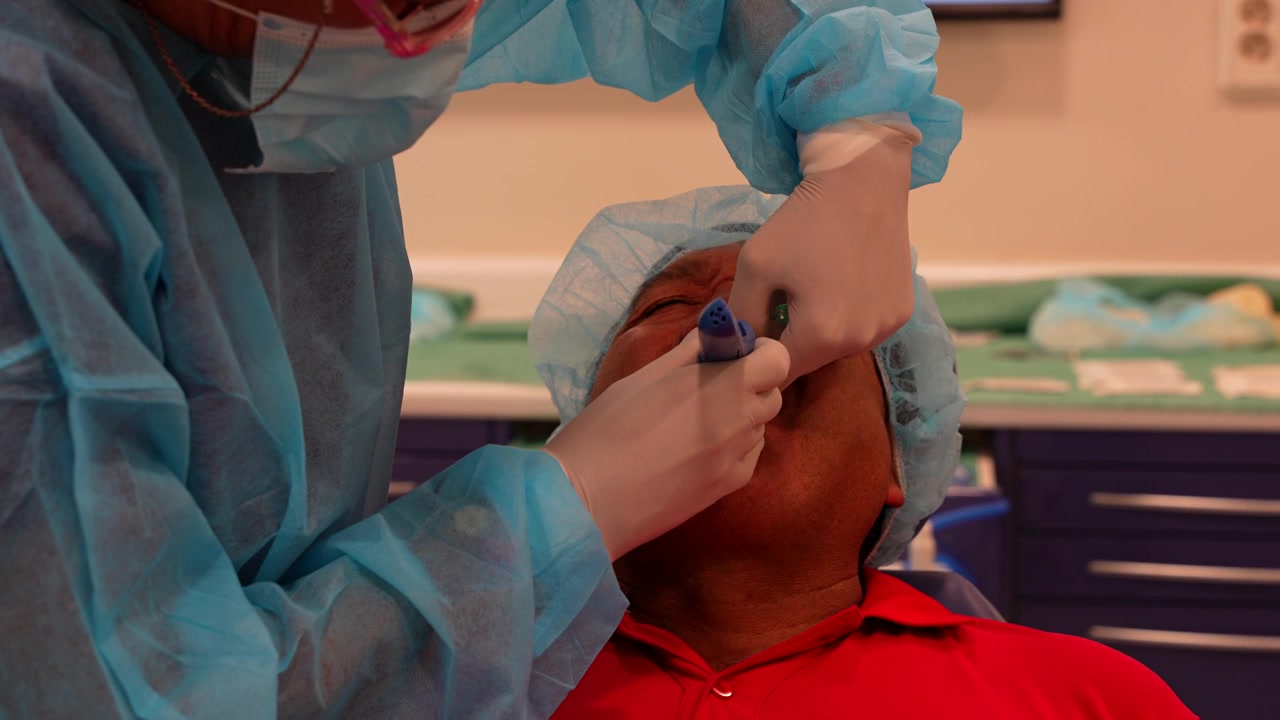 Primo piano di un odontoiatra che applica l'anestesia al suo paziente prima dell'intervento di impianto dentale.