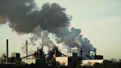 industrial smoke emissions: a continuous view of heavy machinery and atmospheric pollution from a sanitary perspective featuring billowing smoke