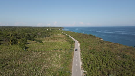 car driving on the road overlooking the blue sea at daytime in summer in sumba island, indonesia