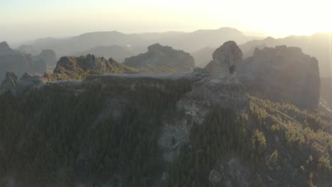 beautiful drone shot at golden hour with lens flare of a mountain panorama with forest of roque nublo, gran canaria