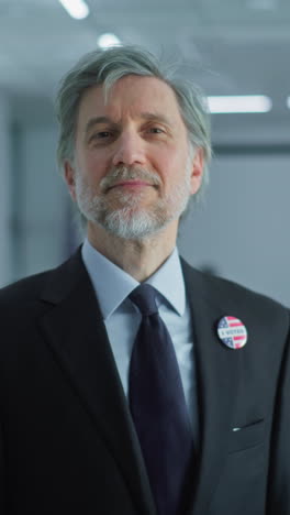 portrait of businessman, united states of america elections voter. mature man stands in a modern polling station, poses and looks at camera, smiles. background with voting booths. civic duty concept.