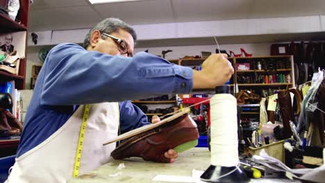 cobbler stitching a shoe sole with needle