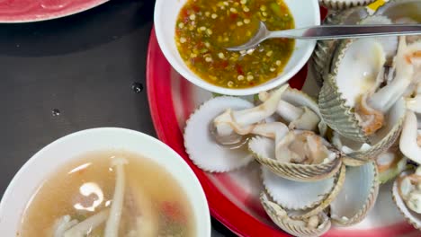 a vibrant selection of thai seafood and spicy salads arranged on plates, captured under bright lighting with overhead camera angles and minimal movement