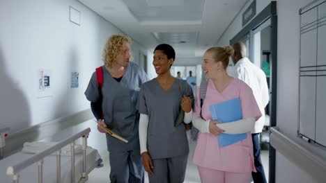 happy diverse doctors talking and walking in corridor at hospital, slow motion