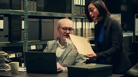 senior inspector showing case details to his partner in archive room