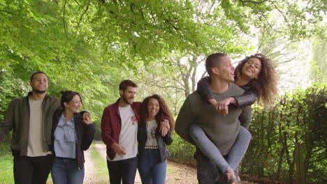 adultos jóvenes caminando y piggybacking en un camino de campo, filmado en r3d