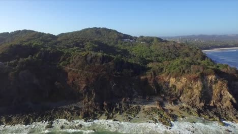 toma aérea de seguimiento de drones de los acantilados de cape byron con olas rompiendo