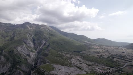 Frontal-drone-video-over-the-"Rrapsh-Serpentine"-mountain-pass-on-the-Sh20-road-in-Grabom,-Albania,-Leqet-e-Hotit-you-can-see-village-houses-and-vehicles