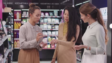 shop consultant selling beauty products to female customers