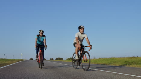 entrenamiento duro. triatleta dos ciclistas entrenando en bicicleta de carretera. dos ciclistas montados en bicicleta de ruta en el parque de la ciudad y preparándose para el triatlón. atleta fit entrenamiento intensivo dos hombres y mujeres en bicicleta antes de la competencia de triatlón