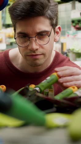 man looking at gardening tools in a store